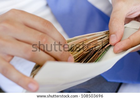 Man in suits is counting how much money in an envelope