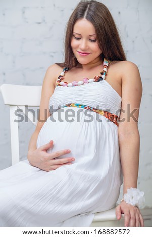 young woman sit on the chair holding his belly