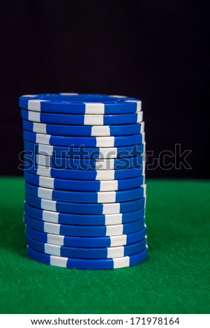 Stack of blue chips on a green playing table with black background