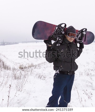 man in dark clothes with a snowboard ski sunglasses on snowy mountainside