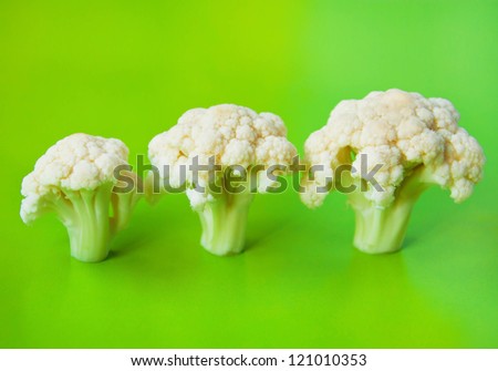 Still life photography of cauliflower sprout standing like trees against bright green background in studio environment