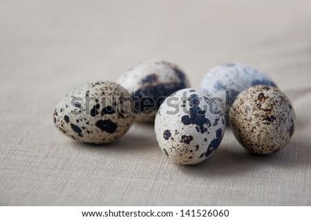 Group of five spotted quail eggs lying on linen cloth. Selective focus. Main focus on egg in the middle