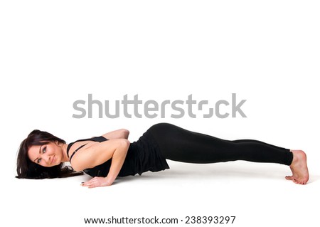 Beautiful woman in black sportswear doing yoga chaturanga pose in studio. Over white background, copy space