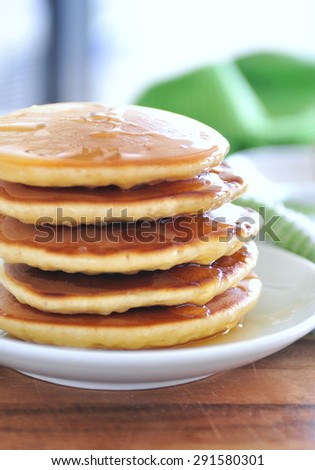 Delicious golden pancakes cooked on dry pan and served for breakfast with honey and kiwi fruit on a wooden board. Still life, copy space, selective focus, main focus on honey reflected at the side