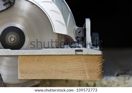 Electric circular saw over wood with sawdust