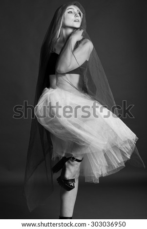 Studio, black and white photo of a girl ballerina, in a flying skirt, on black background
