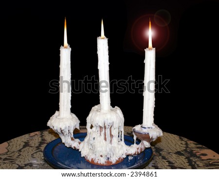 Three candles on a very waxy candle holder