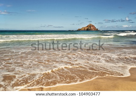 Hawaiian Island; The rugged coastline of the Hawaiian Island of Maui breaks and opens into a tranquil beach with a lone Island in the distance.