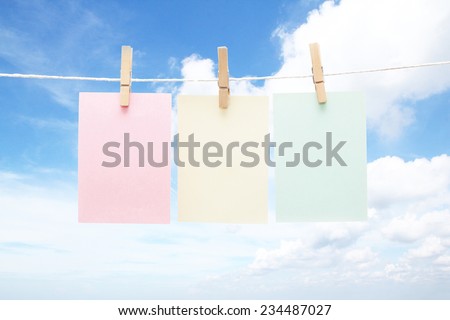 Three colorful pastel notes on wooden clothes pegs on blue sky background
