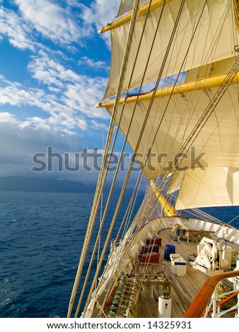 Tall ship under full sails in the sea moving to the island