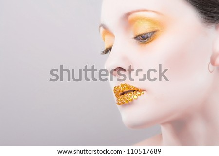 Young caucasian woman with gold fashion makeup and gold diamonties on her lips