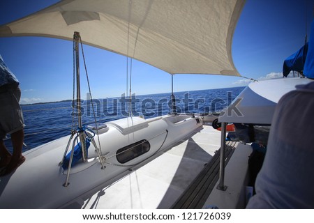 View in front of a boat in the middle of calm blue sea and clear blue sky.