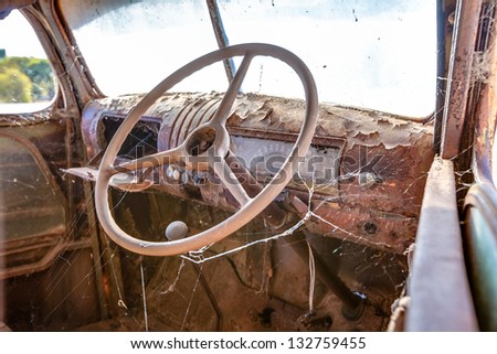 Steering wheel inside an old rusted truck on the side of a highway