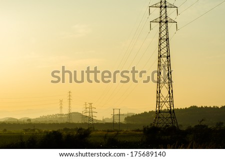 Energy Distribution Network - Electricity Pylons against Orange and Yellow Sunrise