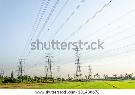 tower for electricity in rural landscape under blue sky