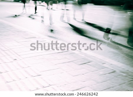 Legs of people in blurred motion with shadows on street.The movement blur makes it spooky
