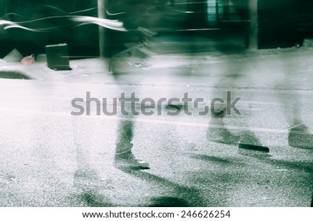 Legs of people in blurred motion with shadows on street.The movement blur makes it spooky