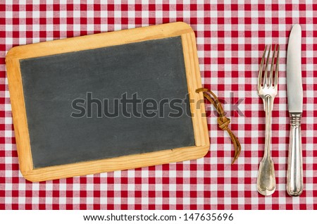 Empty blackboard with silverware on a checkered tablecloth