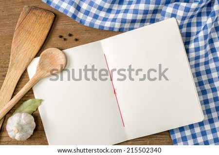 Book with wooden spoons on a blue checkered tablecloth