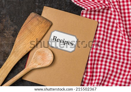Recipe book with wooden spoons on a red checkered tablecloth