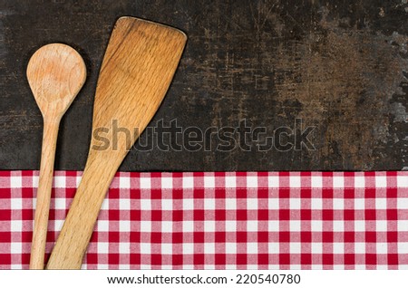 Old baking tray with a red checkered tablecloth and cooking utensils