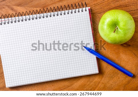 Empty notepad with pen and apple