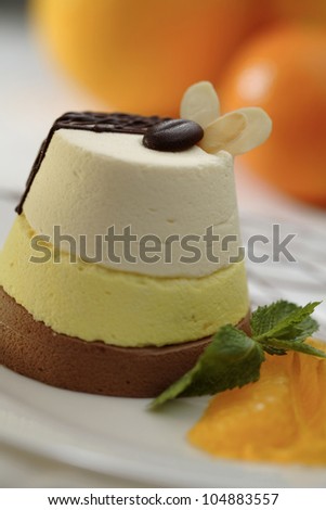 Three-coloured mousse cheese cake with chocolate decoration and oranges