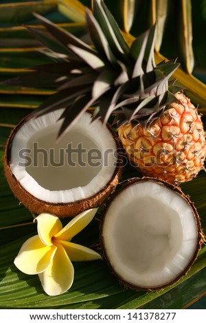 Pineapple and opened coconut with plumeria flower on a palm leaf. Hawaii, Maui, USA