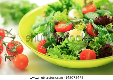 Mixed green salad leaves:   Rocket leaves, Spinach, Basil, Lollo Bionda, Lollo Rosso, Quail eggs  and fresh Cherry Tomatoes  in a  bowl