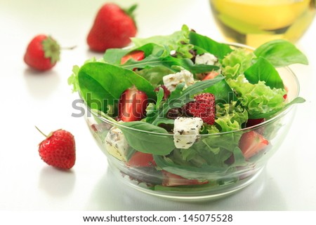 Mixed green salad with Lollo Bionda, Rocket leaves, Spinach, Basil and fresh strawberries in a clear glass bowl