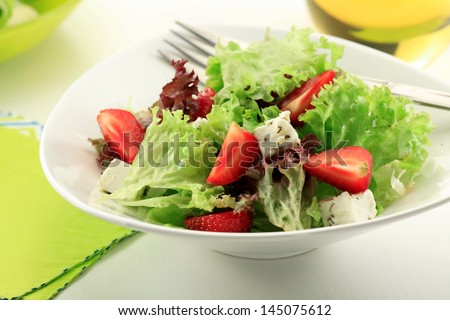 Mixed green salad with Lollo Bionda, Rocket leaves, Spinach, Basil and fresh strawberries in a   glass bowl