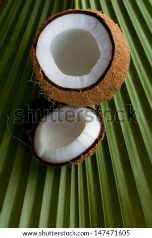 Opened coconut with milk inside on palm leaf