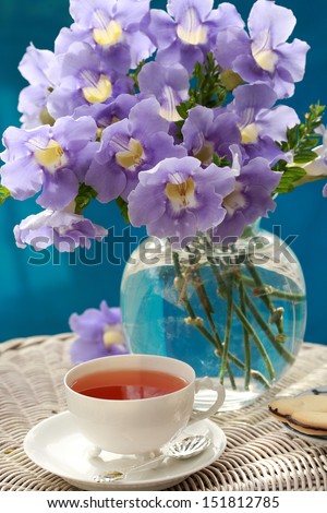 Bunch of Blue Allamanda exotic tropical flowers in a vase and a cup of tea