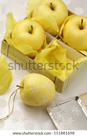 Golden apples in a box decorated to Christmas by snowflakes