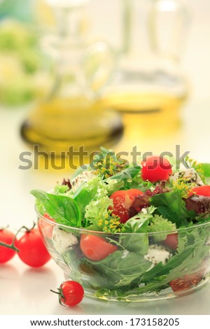 Mixed green salad with  Lettuce, Spinach, Feta  cheese, Lollo rosso, Lollo Biondo  and fresh Cherry Tomatoes  in a  clear glass bowl