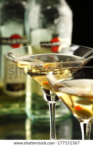 Two martini glasses with martini olives, bottle of the martini on the background