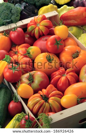 Beefsteak tomatoes, red and yellow tomatoes, broccoli,  zucchini, mallow, bell pepper and eggplants in a wooden box