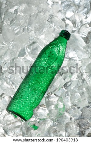 Mineral water bottle of green color on ice cubes background