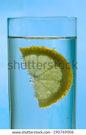 Glass of water with lemon slice isolated on blue background