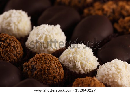 Many assorted chocolates, pralines  and truffles as a background,  ball-shaped chocolates made with black chocolate, white chocolate and milk chocolate