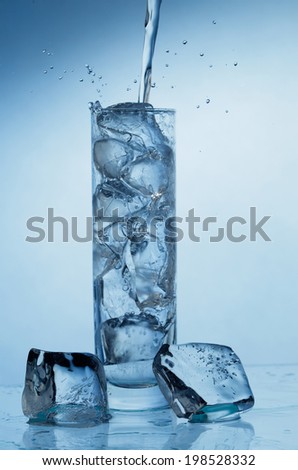 Pouring water into the glass with ice cubes isolated on white background