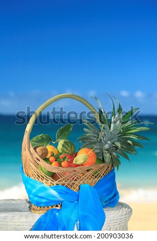 Basket of assorted tropical fruits and flowers, sea on the background. Hawaii, Maui, USA