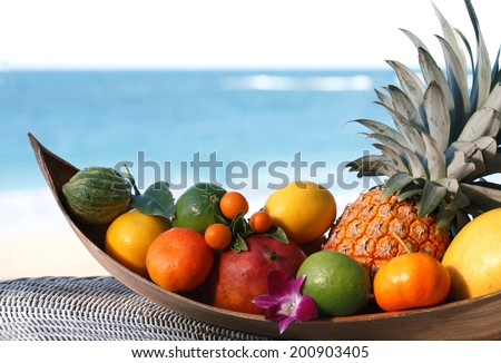 Basket of assorted tropical fruits and flowers, sea on the background