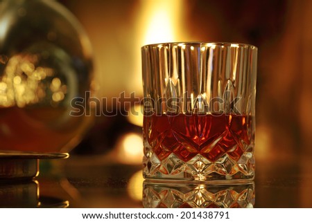 Glass of whiskey and whiskey bottle on the background near the fireplace