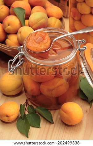 Apricot jam preserved in a jar and a basket of fresh apricots on the background