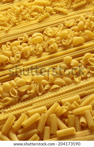 Variety of uncooked pasta with spaghetti, fusilli, shell pasta as a background