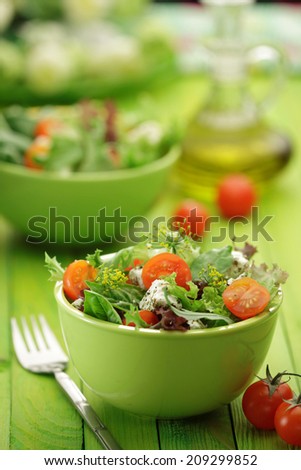 Mixed green leaves salad with  Feta cheese, Rocket leaves, Lettuce, Spinach, Basil,   cherry tomatoes  in a  glass bowl