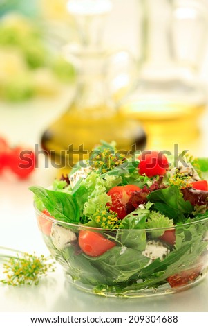 Mixed green leaves salad with  Lettuce, Spinach, Feta  cheese, Lollo rosso, Lollo Biondo  and  Cherry Tomatoes  in a   glass bowl. Greek salad