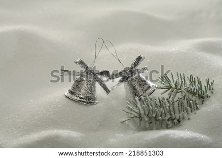 Christmas still:  white snow surface, fir tree branch  and Christmas bells