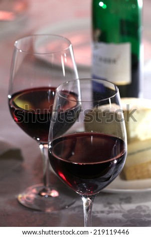Two glasses of red wine, bottle of red wine a cheese  still life